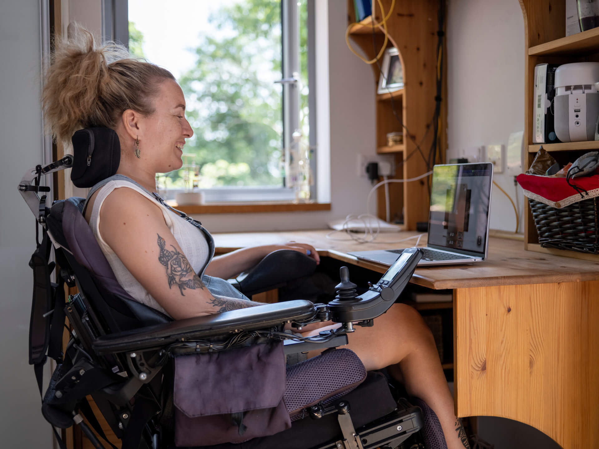 Frau im elektrischen Rollstuhl arbeitet an einem Laptop